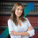 A woman in a blouse stood in front of law books, smiling, chartered corporate commercial surveyor, business rates assessment