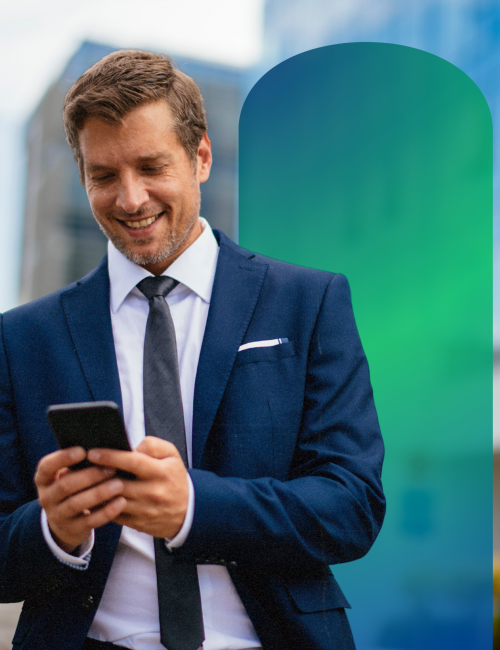 A man in a suit outside smiling looking at his phone