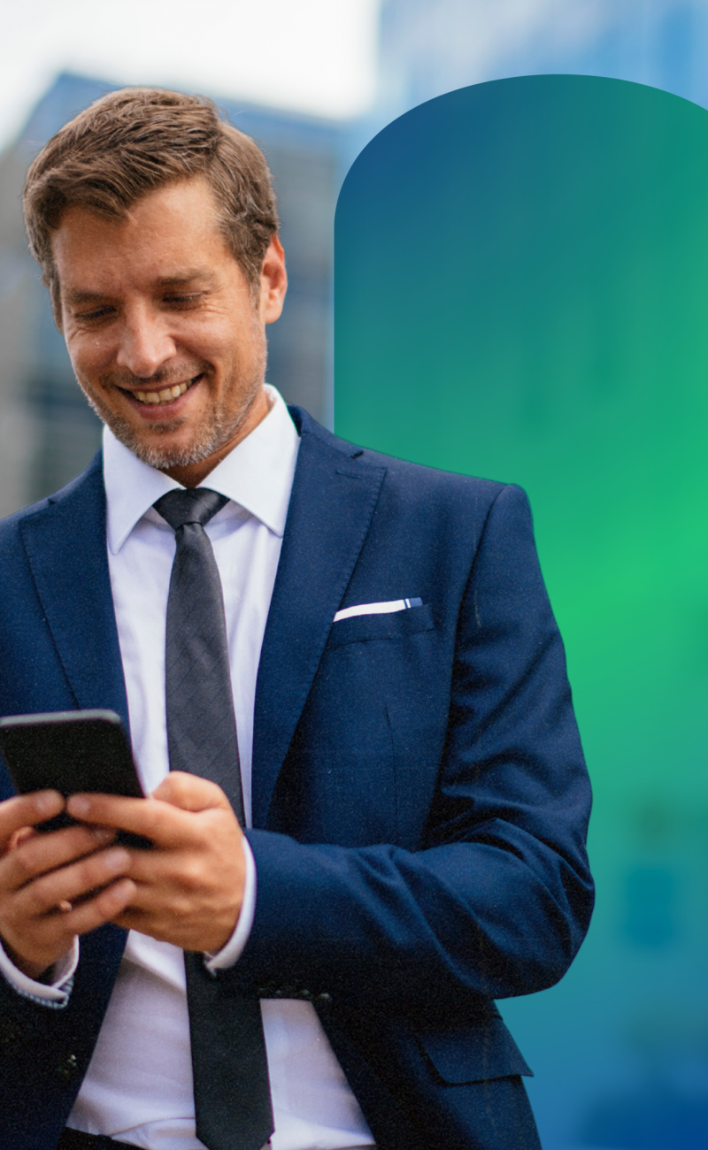 A man in a suit outside smiling looking at his phone